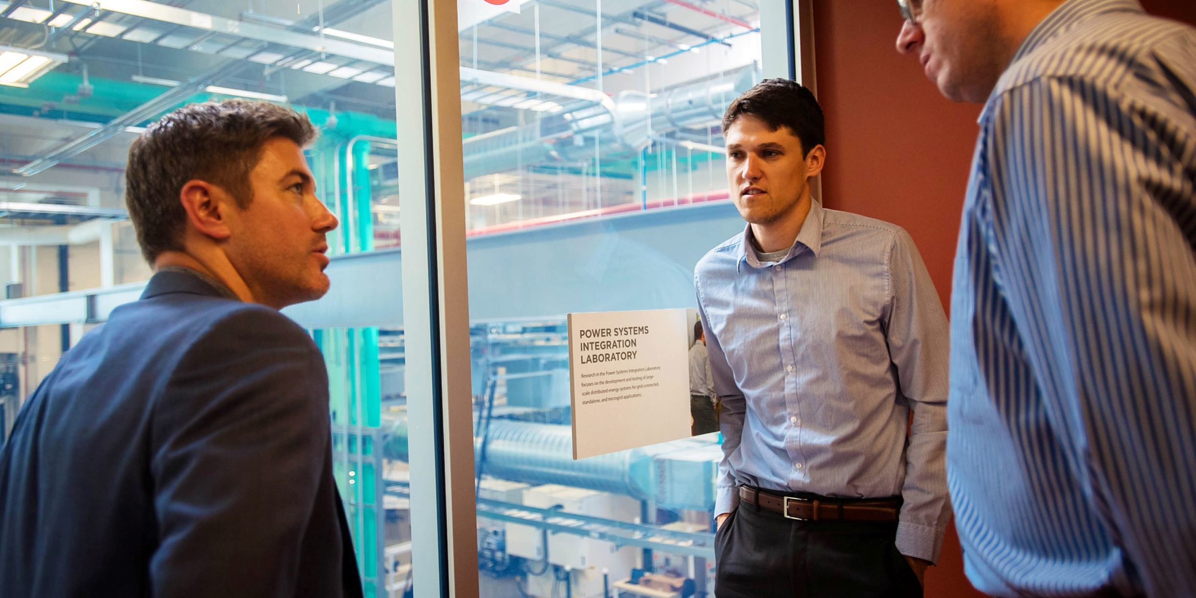 Three men looking out over a laboratory
