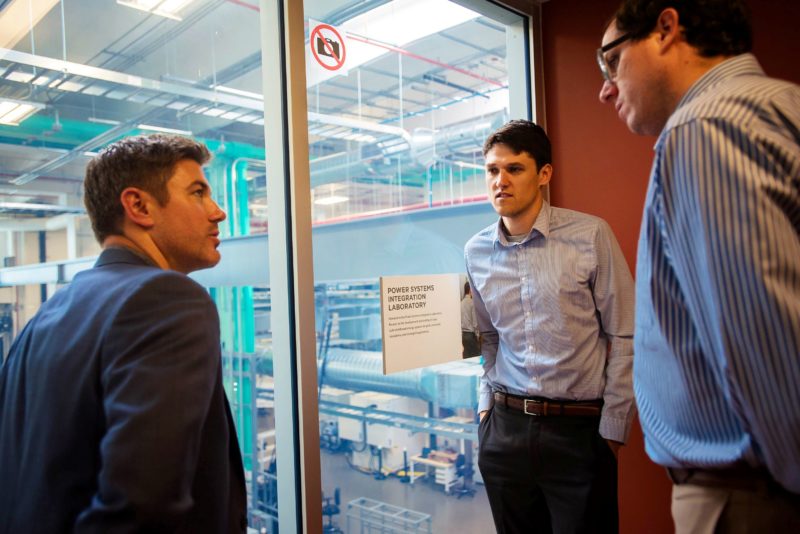 Three men looking out over a laboratory